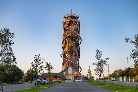Blick über den Parkplatz zum hölzernen Turm mit Erlebnisrutsche und davorliegendem Eingangsgebäude