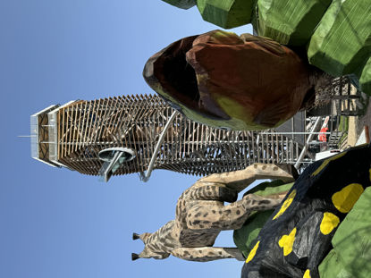 hölzerner Turm mit Erlebnisrutsche und Skywalk, davor Holzfiguren in Form von Tieren